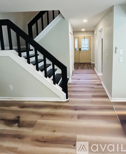 A hallway with a staircase and a wooden floor.