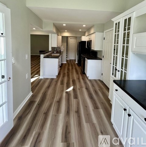 A kitchen with white cabinets and a black countertop.