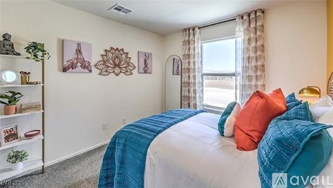 A bedroom with a bed covered in a blue and orange blanket.