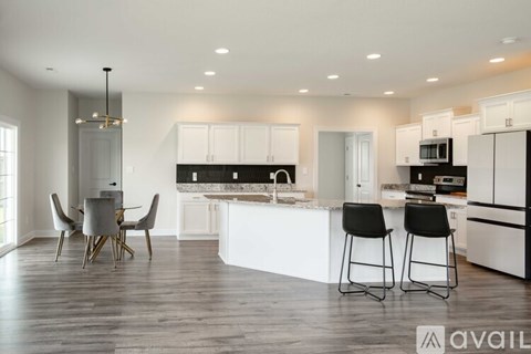 A modern kitchen with white cabinets and black bar stools.