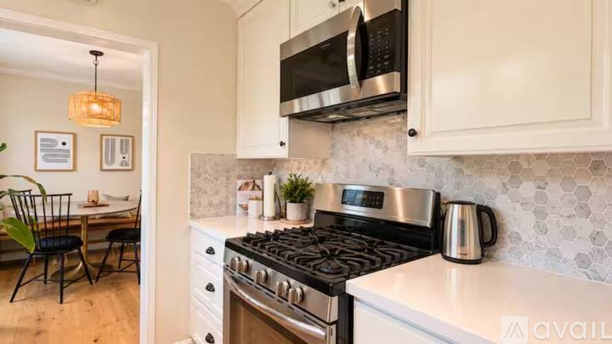 A kitchen with a black stove top and white cabinets.