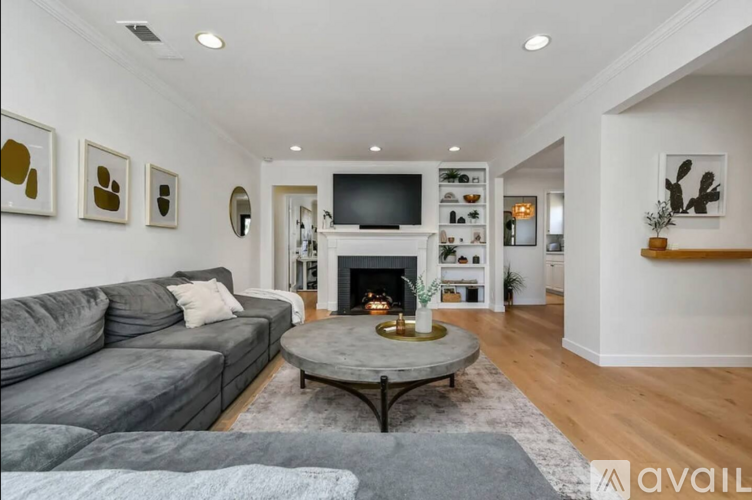 A living room with a grey couch and a fireplace.