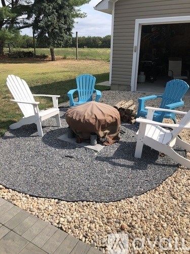 Four chairs and a bean bag are arranged on a gravel patio.