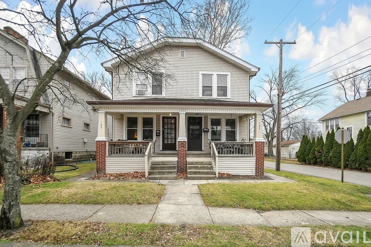 A house with a front porch and a tree in front.