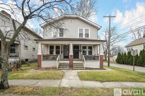 A house with a front porch and a tree in front.