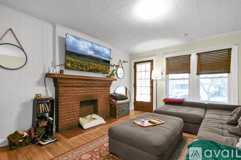 A living room with a grey sofa, a fireplace, and a TV mounted on the wall.