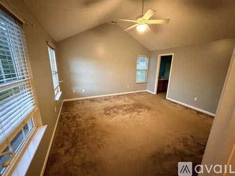 A room with a ceiling fan and a window with blinds.