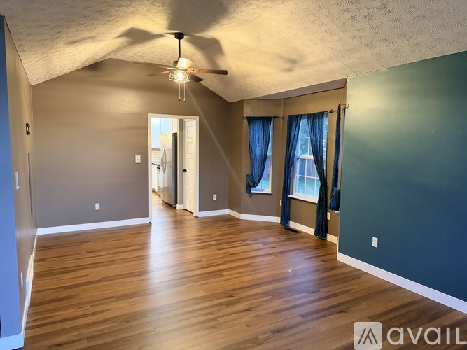 A spacious room with wooden floors and a ceiling fan.