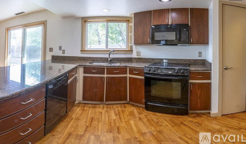 A kitchen with wooden floors and a black stove top oven.