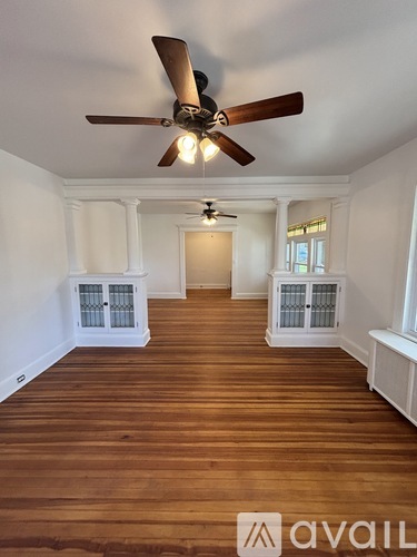 A room with a ceiling fan and wooden flooring.