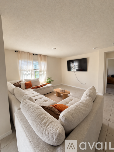 A living room with a large couch and a flat screen TV mounted on the wall.