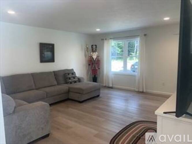 A living room with a grey couch and a television on a white stand.