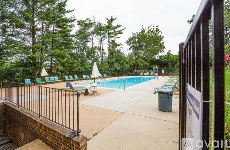 A pool surrounded by trees and a fence.