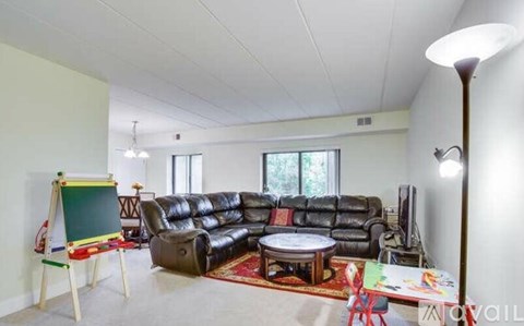 A living room with a black leather couch and a small chalkboard.