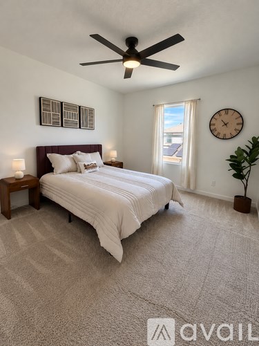 A bedroom with a bed, a ceiling fan, and a clock on the wall.