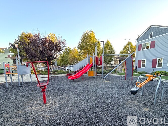 A playground with a red swing set and a red slide.