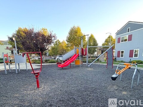 A playground with a red swing set and a red slide.