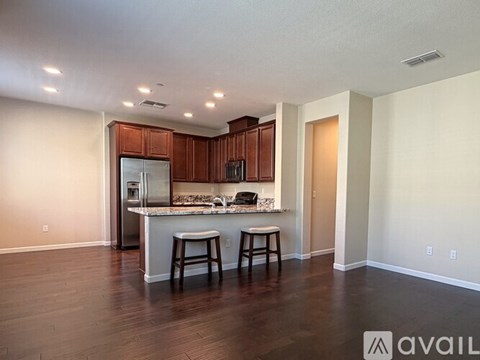 A kitchen with wooden cabinets and a white countertop with two stools.