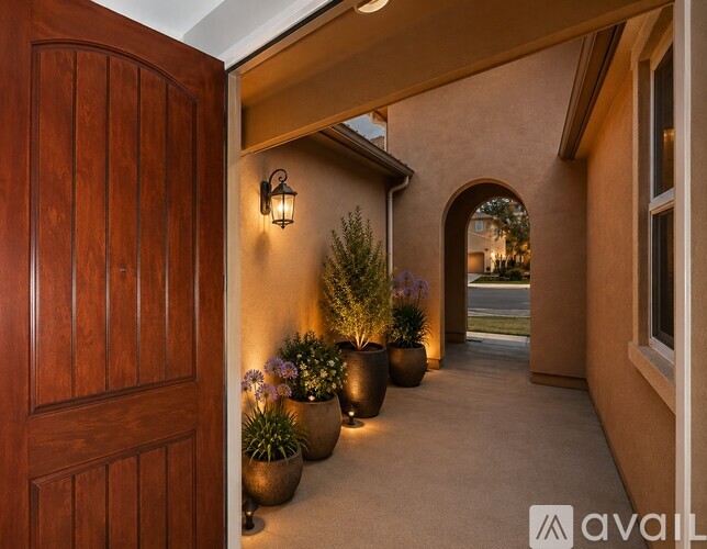 A wooden door opens to a hallway with potted plants and a lantern.