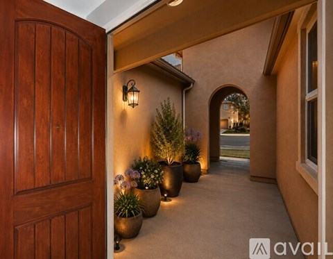 A wooden door opens to a hallway with potted plants and a lantern.