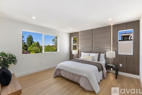 A bedroom with a large bed and a window overlooking a tree.
