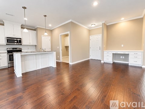 A kitchen with white cabinets and a wooden floor.