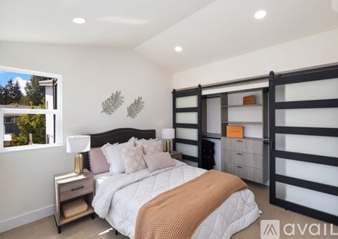 A bedroom with a large bed and a window overlooking trees.