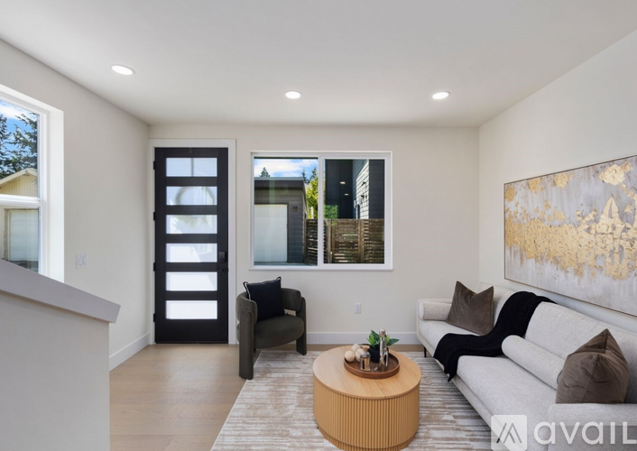 A modern living room with a grey couch, a wooden coffee table, and a large painting on the wall.