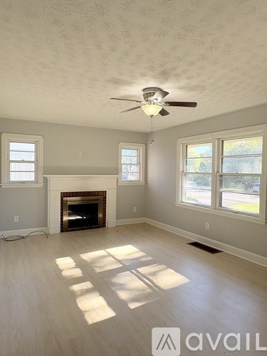A living room with a fireplace and a ceiling fan.