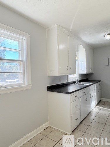 A kitchen with white cabinets and a black countertop.