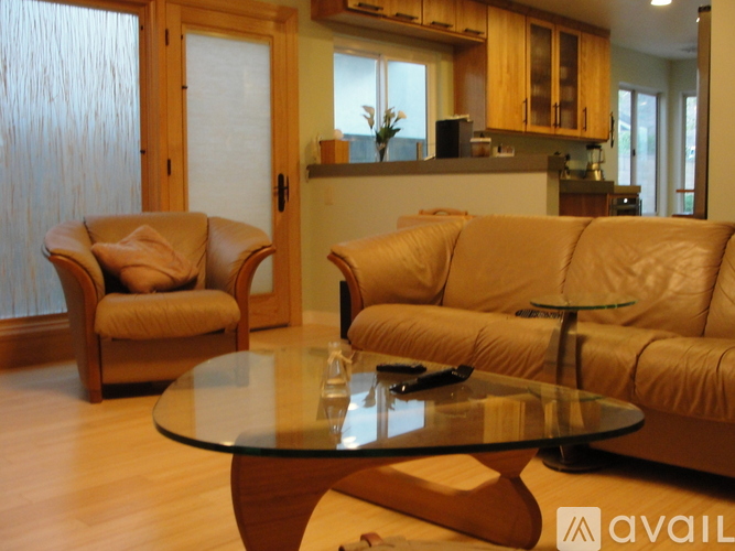 A living room with a glass table and two leather sofas.