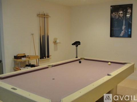 A pool table in a room with a poster of Hamlet on the wall.