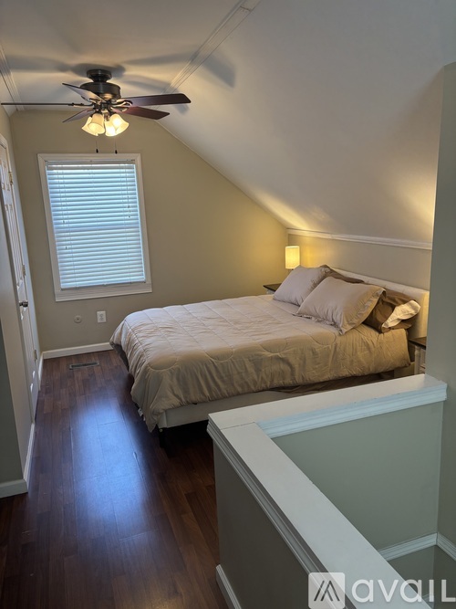 A bedroom with a bed, a ceiling fan, and a window with blinds.