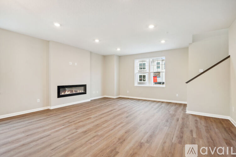 A spacious room with a fireplace and wooden flooring.
