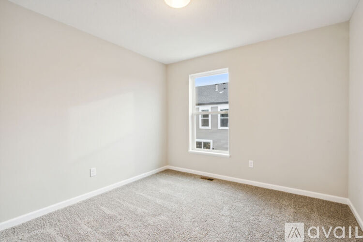 A room with a carpeted floor and a window showing a building outside.
