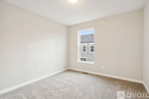 A room with a carpeted floor and a window showing a building outside.
