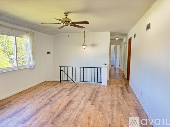 A spacious room with a ceiling fan and wooden flooring.