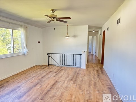 A spacious room with a ceiling fan and wooden flooring.