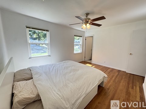 A bedroom with a bed, a ceiling fan, and a window with a view of the outside.