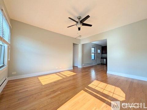A spacious room with a ceiling fan and wooden flooring.