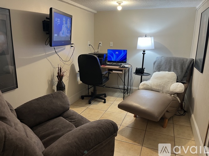 A living room with a couch, chair, and a television mounted on the wall.