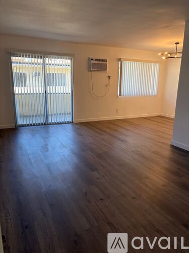 A room with wooden floors and a window with blinds.