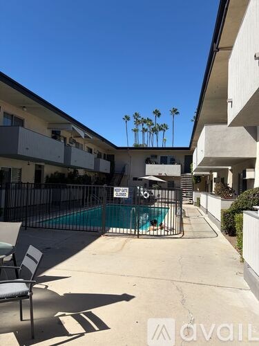 A pool surrounded by a fence and a chair.