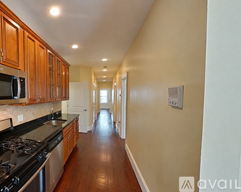 A long hallway with a kitchen on the left side.