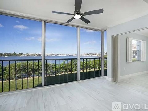 A spacious room with a ceiling fan and a view of the ocean through large windows.