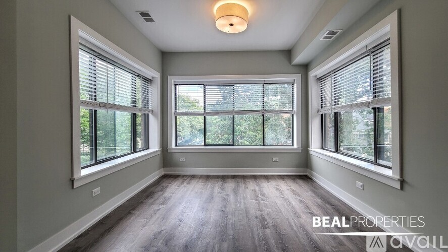 A spacious room with large windows and wooden flooring is on the market.