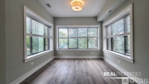 A spacious room with large windows and wooden flooring is on the market.