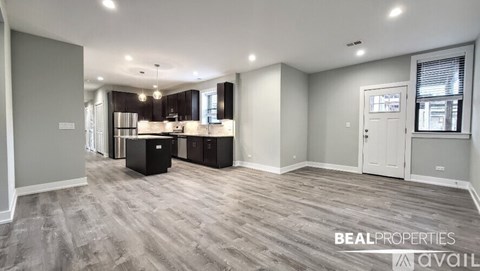 A spacious room with a kitchen area and a dining table.