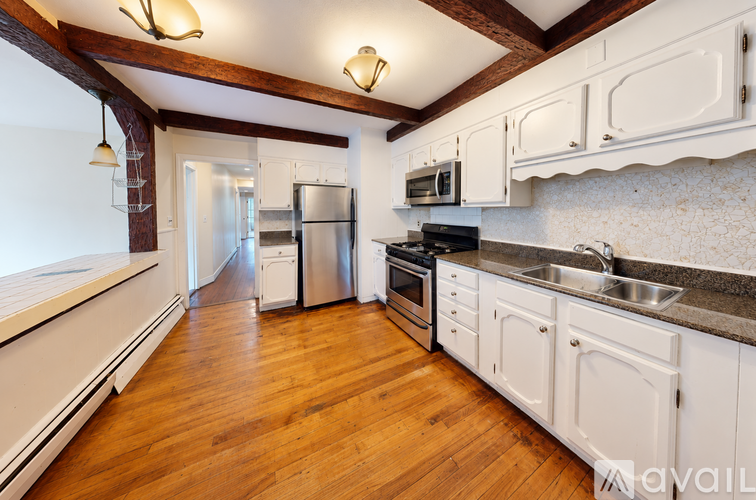 A kitchen with white cabinets and a wooden floor.