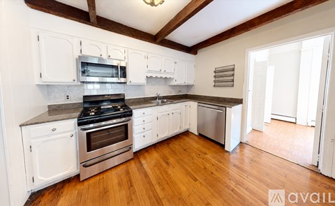 A kitchen with white cabinets and a wooden floor.